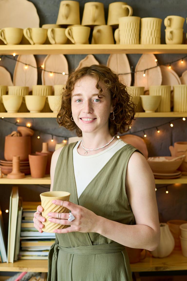 A young potter maker standing in their shop.