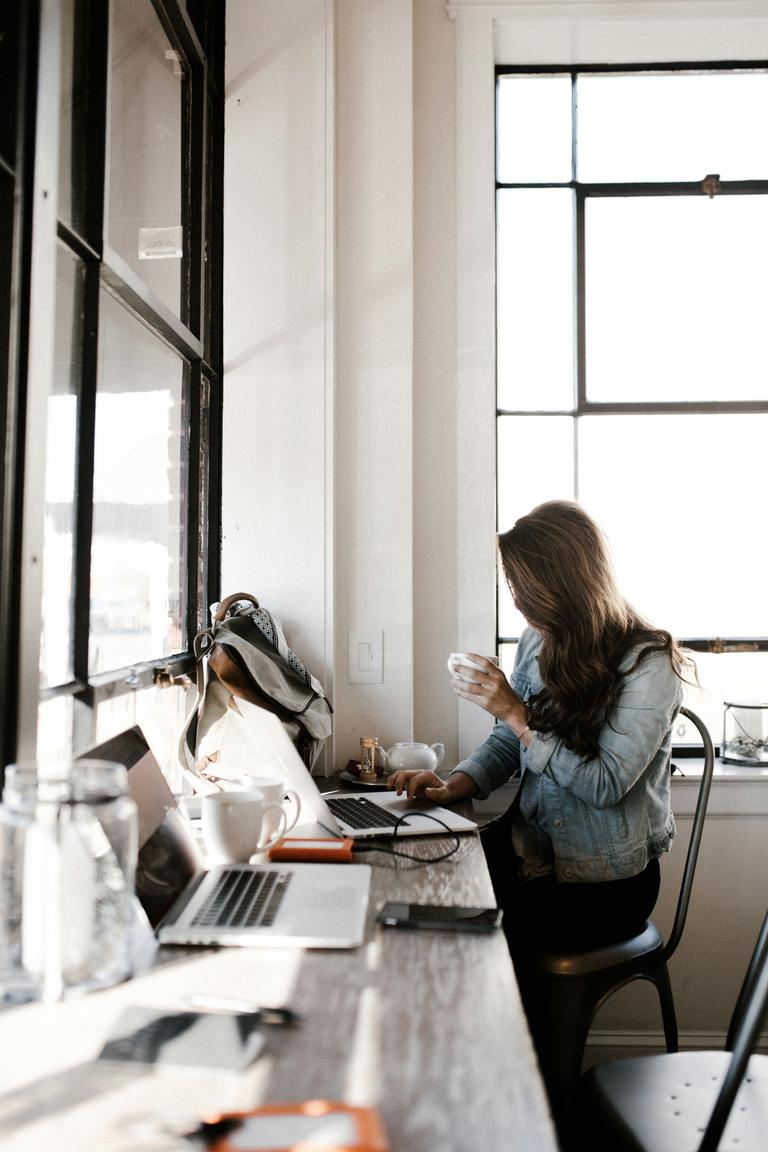 A woman working on her laptop in a cafe.