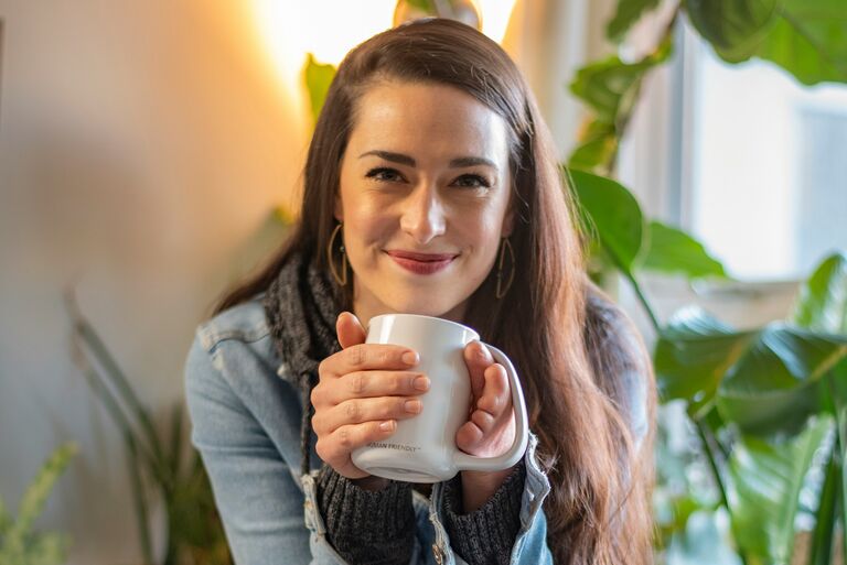 A woman smiling with a cup of coffee.