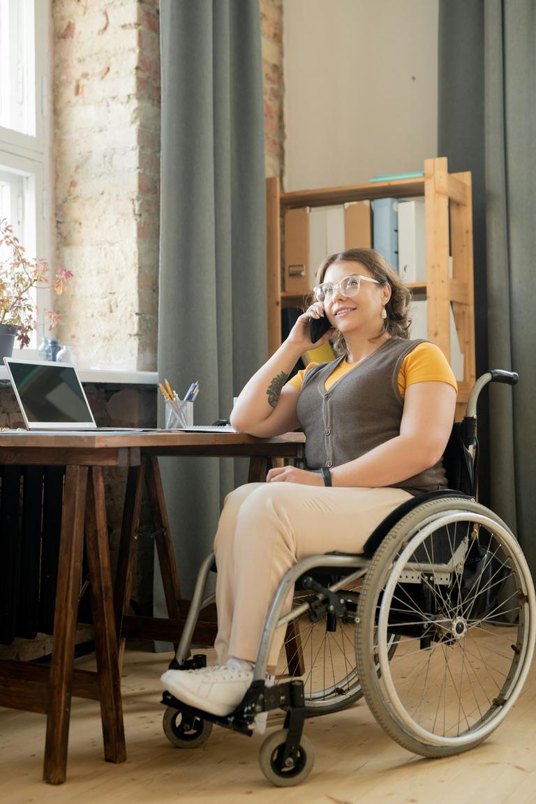 A woman in a wheelchair talking on the phone.