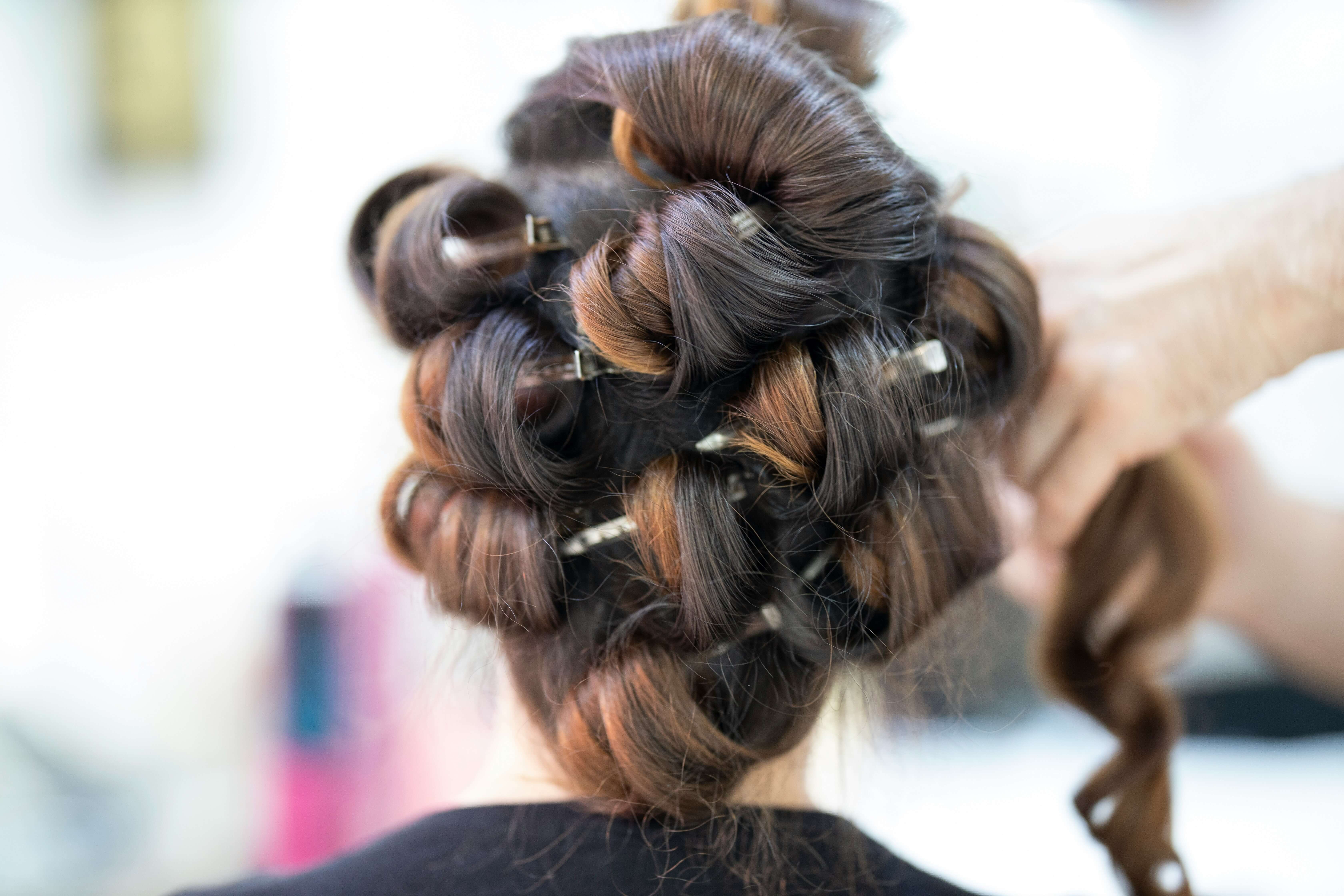 A woman getting curls done on her hair.